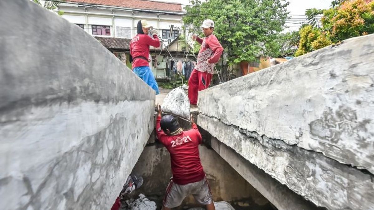 洪水を防ぐために浚渫スラバヤ村の排水堆積物