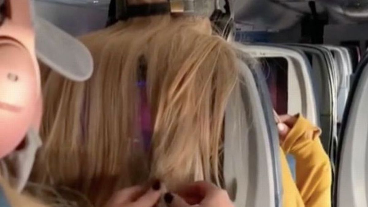 另一位乘客因为挡住飞机上的电视而粘在女人的病毒性头发上