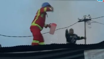 لحظة ضابط يكسر بسرعة مع الماء في إبريق للشاي أثناء مكافحة حريق في ساماريندا