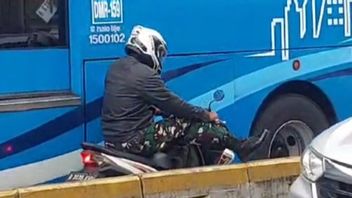 Sur la Honda Beat, un membre uniforme du TNI qui craint Kena Razia sur la ligne de bus, tournant en arrière