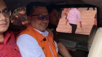 Le chef de l’éducation de Riau, un suspect de corruption, sourit lorsqu’il a été conduit dans une voiture d’attente