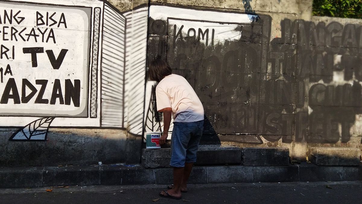 役員は、地元住民の手を通してケボンカカンの社会的批判の壁画を削除します