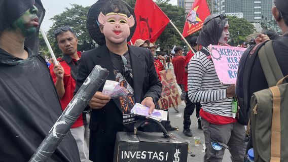 Des travailleurs de la manifestation du jour de May à Jakarta portent un masque de porc en uniforme avec le patron de la société sentil injustice